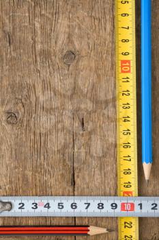 pencil and tape measure on wood texture
