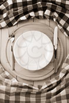 plate, knife and fork at cutting board on wooden background