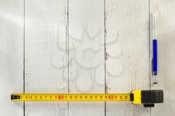 tape measure and pencil on wooden texture