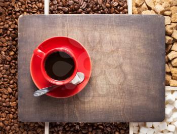 cup of coffee and beans on wooden tray background, top view