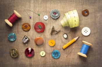 sewing tools and accessories on wooden table background, top view