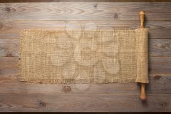 rolling pin and sacking burlap at wooden board rustic  plank table background, top view