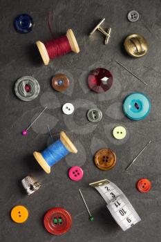 sewing tools and accessories on slate stone background, top view