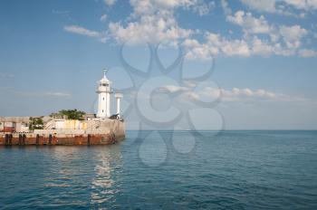 Beacon in Yalta. The dark blue sky with clouds, the sea, a mooring.
