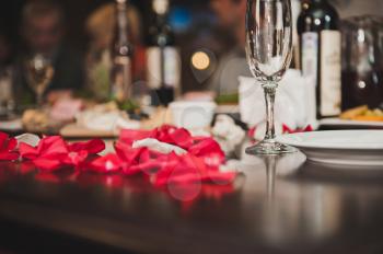 Table with wine and petals of roses.