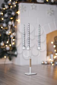 Triple candle holder with beautiful patterned candles on the background lights Christmas garlands.