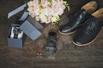 Shoes, rings and a bouquet with a clock on the table.