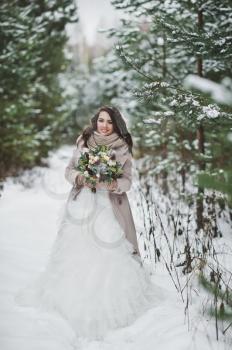 Bride against the winter snow-covered forest of firs and pines.