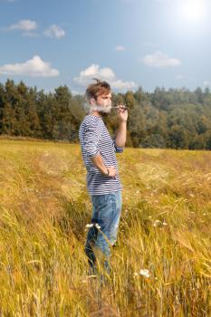  man in a striped vest on the nature in the field of e-cigarette