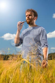 man in a striped vest on the nature in the field of e-cigarette