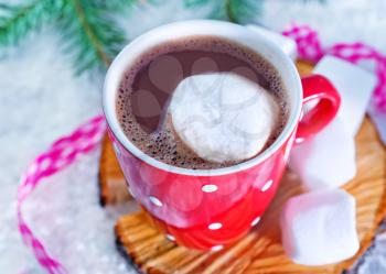 cocoa drink with marshmallows in cup and on a table