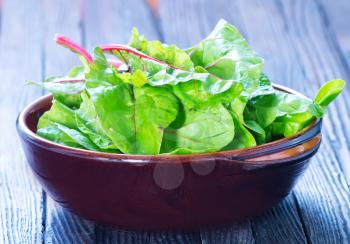 fresh spinach in bowl and on a table