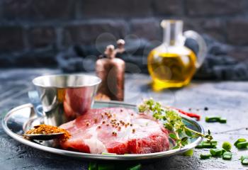 meat with spice on metal plate and on a table