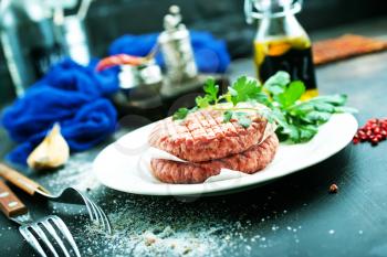 raw burgers on white plate with spice and salt