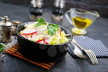 salad from fresh cabbage and radish, salad in black bowl