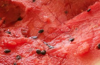 Natural healthy vegetarian foods fresh fruit background: red ripe watermelon chaotically sliced with watermelon seeds closeup view, photo with shallow depth of field
