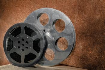 Two reels with a film on a wooden background