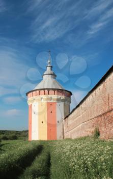 Watch tower of Spaso-Prilutsky Monastery in the Vologda city, Russia. Blue sky and green grass. Castle defense wall