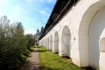 Arcade of the ancient courtyard of Spaso-Prilutsky Monastery at summer sunny day in in the Vologda, Russia. Blue sky and green grass. Castle defense wall