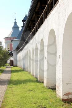 Arcade of the ancient courtyard of Spaso-Prilutsky Monastery at summer sunny day in in the Vologda, Russia. Blue sky and green grass. Castle defense wall