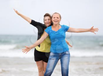 Two pretty young smiling women on the beach with open arms enjoying their freedom. Shallow depth of field.