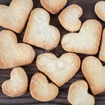Delicious cookies in the shape of hearts on a wooden table. Top view.