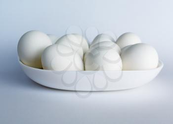White eggs on a white plate on a light background