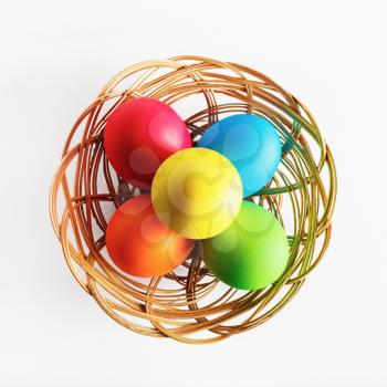 Bright colorful easter eggs in a wicker basket. Top view.