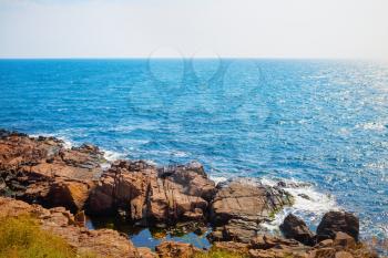 Black Sea coast in a hot summer day. Rocky coast with bright blue sea water and large stones.