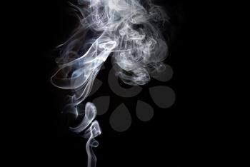 Photo of abstract smoke swirls over black background. Studio shot.
