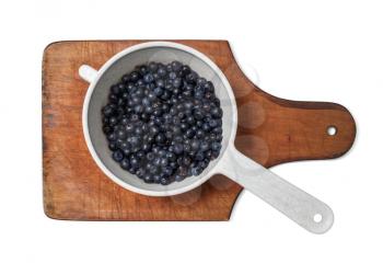 Blueberries in a dipper on a cutting board. Clipping path.