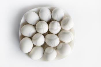 White eggs on a plate on a light background.