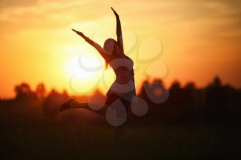 Woman with arms raised dancing against the sunset background. Shallow depth of field. Selective focus on model.