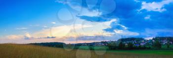 Meadow and sunset sky with clouds in the countryside. Panoramic shot.
