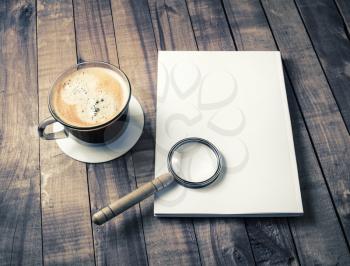 Photo of blank closed booklet, magnifier and coffee cup on wood background. Responsive design mockup.