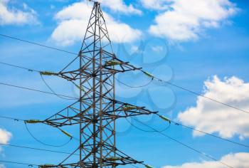 High voltage tower. Electricity pylon silhouetted against blue sky background.