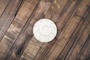 Blank wooden beer coaster on wood table background. Flat lay.