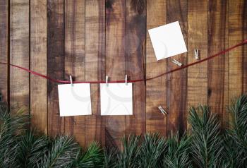 Blank photo paper attach to rope with clothespins on wood table background. Flat lay.