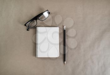 Photo of blank notebook, glasses and pencil on craft paper background. Top view.
