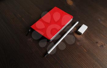 Red notebook, pencil and eraser on wooden background. ID mockup. Responsive design template.