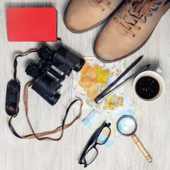 Preparation for travel. Tourist devices. Traveler's accessories on light wood table background. Planning vacation. Top view. Flat lay.