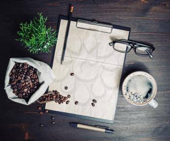 Menu and coffee. Clipboard with blank kraft letterhead, coffee cup, coffee beans, glasses, pencil and plant on wooden background. Top view. Flat lay.