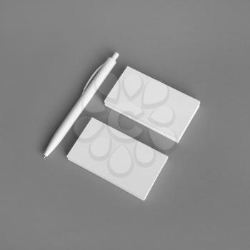 Blank business cards and pen on gray paper background. Branding mock up.
