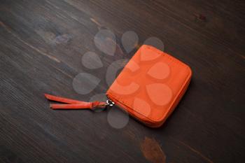Orange pocket purse bag on wood table background. Small fabric cosmetic bag or wallet bag.