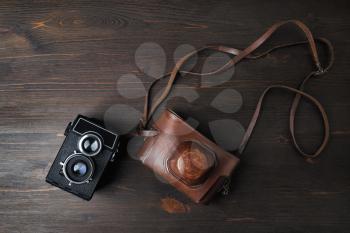 Vintage photo camera on wood table background. Top view. Flat lay.