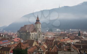 Panoramic  view of Brasov old town and Black Church with the Carpathian Mountains in a foggy winter day. Transylvania, Romania