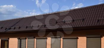 The roof of corrugated sheet on a building. Brown roofing metal sheets on Rented store. Brown shutters on the windows.