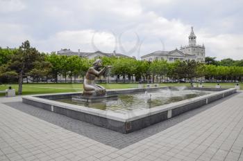 Statue of kneeling woman in the fountain. Water flowing from the hands of the statue.