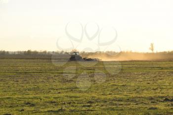 Tractor at sunset plow plow a field. Tilling the soil in the fall after harvest. The end of the season.