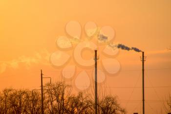 Smoke from the boiler pipes at sunset. Winter landscape.